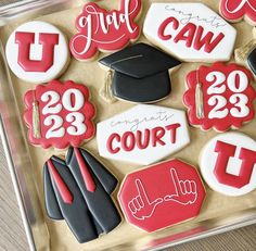 decorated cookies in the shape of graduation caps, gowns and numbers are displayed on a tray