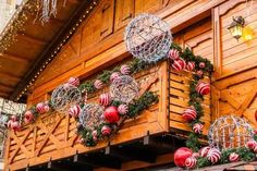 christmas decorations are hanging on the side of a wooden building with lights and baubles