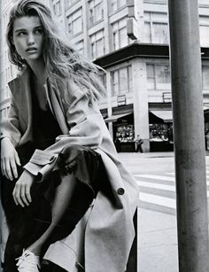 a black and white photo of a woman sitting on a pole