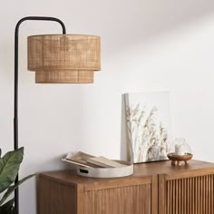 a wooden cabinet with a lamp and pictures on the shelf next to it in front of a white wall