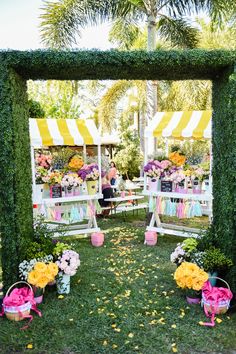 an outdoor ceremony with flowers and decorations on the grass, in front of a yellow striped tent