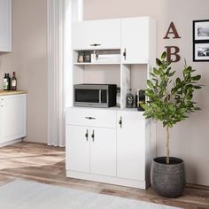 a white cabinet with a microwave on top and a potted plant next to it