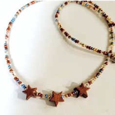 Artist Designed Petite Beaded Necklace With Beautiful Dark Hardwoods Cut Star Beads. Combined With A Classic Color Collection Of Bronze, Blue, Brown, And Gold Rimmed Clear Glass Seed Beads, It Is A Fun All Season Look. Style Is Short Choker, But Has A 2 Inch Extension Chain For Perfect Sizing Adjustments. Length: 14.5 With A 2 Inch Extension Chain. * Custom Sizing Is Available On Request. Casual Brown Beaded Necklaces With Colorful Beads, Star-shaped Beaded Necklaces For Festivals, Brown Wooden Beaded Necklaces For Festivals, Star Beads, Boho Denim, Layered Choker Necklace, Choker Collar Necklace, Layered Necklaces Silver, Layered Chokers