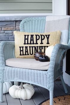 a blue wicker chair with a happy halloween pillow sitting on it's back