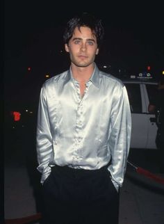 a man in a silver shirt and black pants