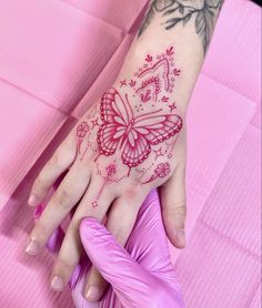 a woman's hand with a butterfly tattoo on it and pink gloves next to her