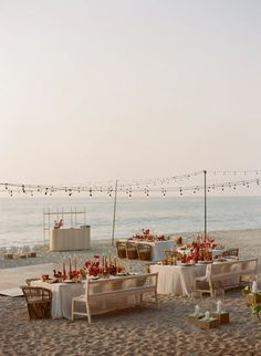 an outdoor dining area on the beach with chairs and tables covered in white linens