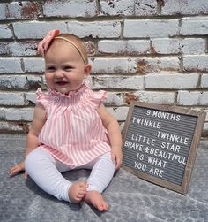 a baby sitting on the ground next to a sign