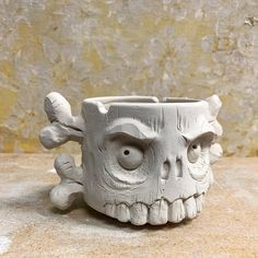 a white ceramic skull mug sitting on top of a stone counter next to a wall