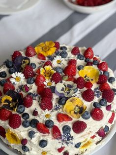 a cake with berries, strawberries and blueberries on it sitting on a table