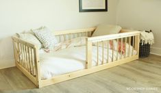 a wooden crib with white sheets and pillows on the bottom bed in a bedroom