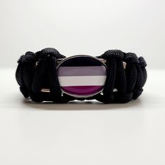 a purple and white striped bracelet with black cords