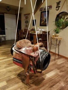 a horse's saddle hanging from a ceiling in a room with wooden floors and walls