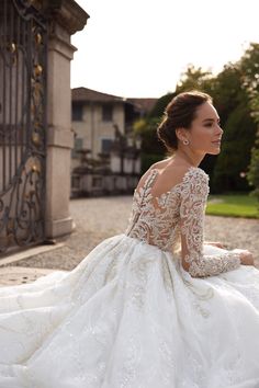 a woman sitting on the ground wearing a wedding dress with long sleeves and open back