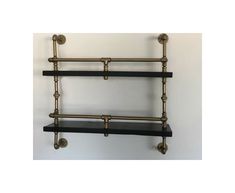 two black shelves with brass pipes on them