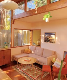 a living room filled with furniture and windows next to a wooden floor covered in plants