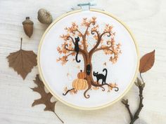 a cross stitch pattern with two cats sitting on a tree and pumpkins in the background