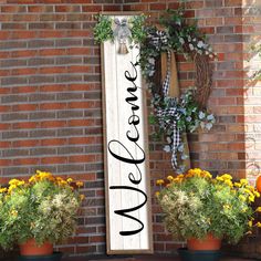 a welcome sign sitting on top of a brick wall next to some potted plants