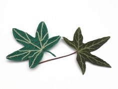 two crocheted leaves sitting next to each other