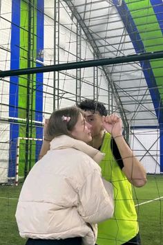 a man and woman standing in front of a soccer goal