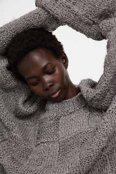 a woman in grey sweater holding her head with both hands