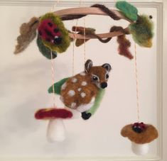 an animal mobile hanging from a tree branch with mushrooms and ladybugs on it