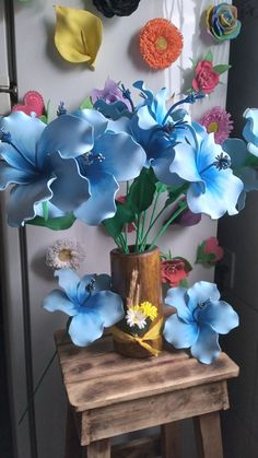 a vase filled with blue flowers sitting on top of a wooden table next to a wall