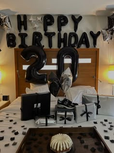 a birthday party with balloons and presents on the bed, including a cake in the shape of a number