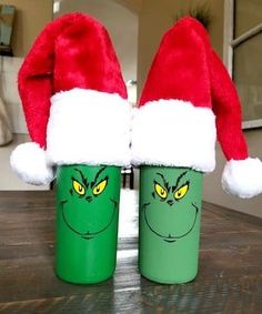 two green cups with grin - face faces on them are sitting on a wooden table