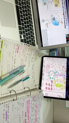 an open laptop computer sitting on top of a desk next to a notebook and pen