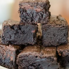 chocolate brownies stacked on top of each other in front of a glass of milk