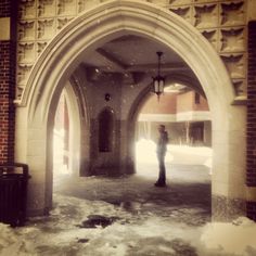 a person standing in the middle of an archway with snow all around them and lights on