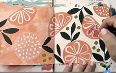 someone is painting an orange and black flower on a piece of paper with watercolors