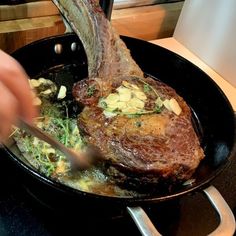 a person is cutting into some food in a skillet on the stove with a pair of tongs