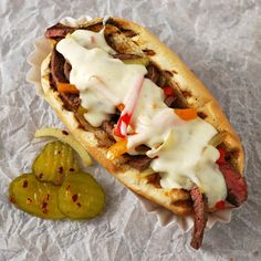 a hot dog on a bun with toppings and pickles