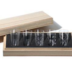 an assortment of glasses sitting on top of a wooden box next to another set of glasses