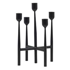 four black candlesticks are arranged in the shape of three poles and one candle holder