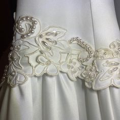 the back of a white dress with pearls on it