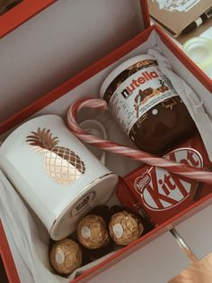 an opened box containing two mugs and some candy canes with chocolate in them