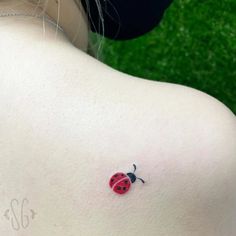 a ladybug tattoo on the back of a woman's shoulder