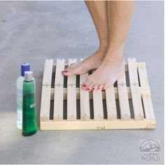 a woman standing on top of a wooden pallet next to a bottle