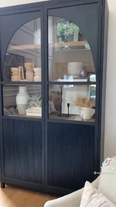 a black china cabinet with glass doors and shelves