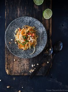 a plate filled with noodles and vegetables on top of a wooden cutting board