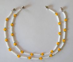 two strands of white beads with yellow flowers on them