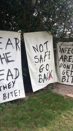 three signs with words written on them in front of a tree and grass covered yard