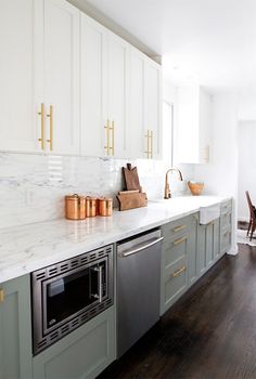 a kitchen with white cabinets and gold handles