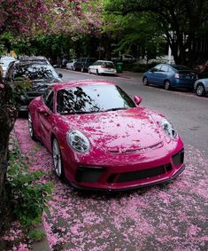 a red sports car parked on the side of a road with pink flowers all over it