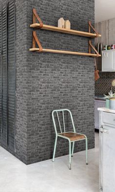 a chair sitting in front of a brick wall next to a stove top oven and microwave