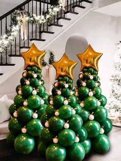 a christmas tree made out of balloons with gold stars on top and green balls in the middle