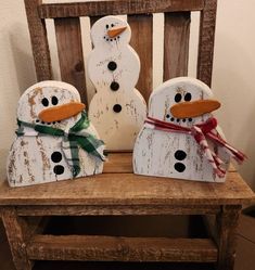 two snowmen sitting on top of a wooden bench